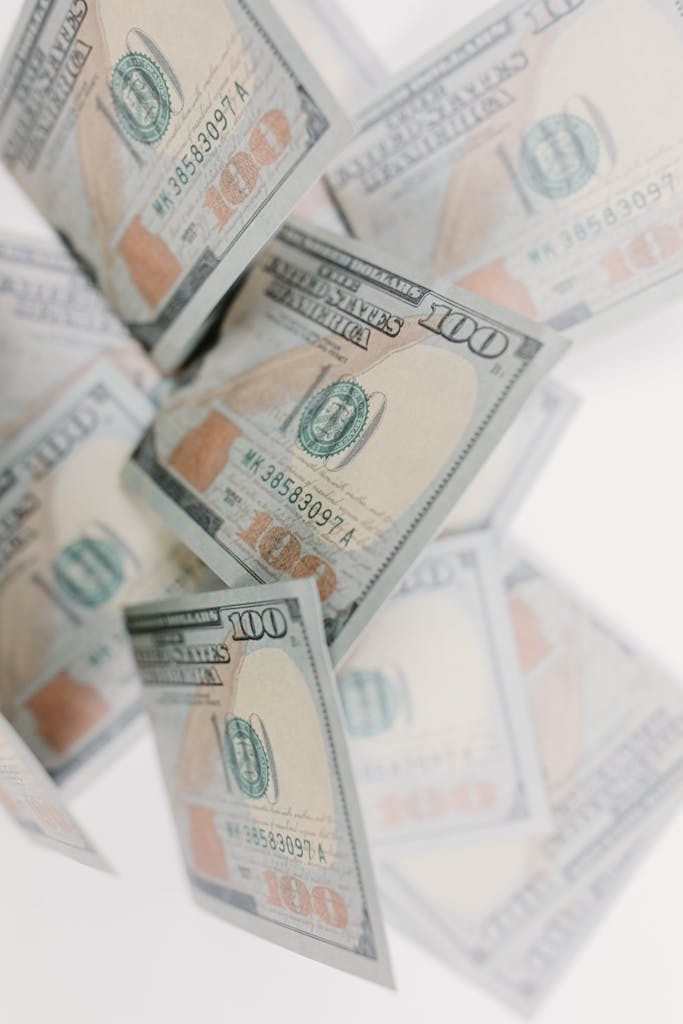 A collection of 100 dollar bills floating against a white background, emphasizing wealth and finance.