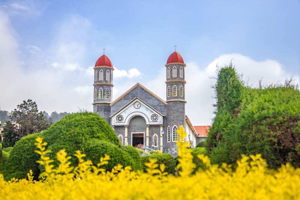 Beautiful view of Iglesia de San Rafael amidst lush gardens and blue sky.
