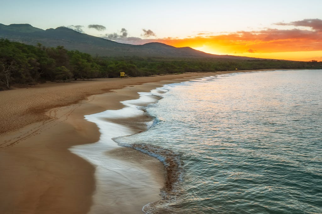 Serene sunset at Makena Beach, Maui, with ocean waves lapping the shore.