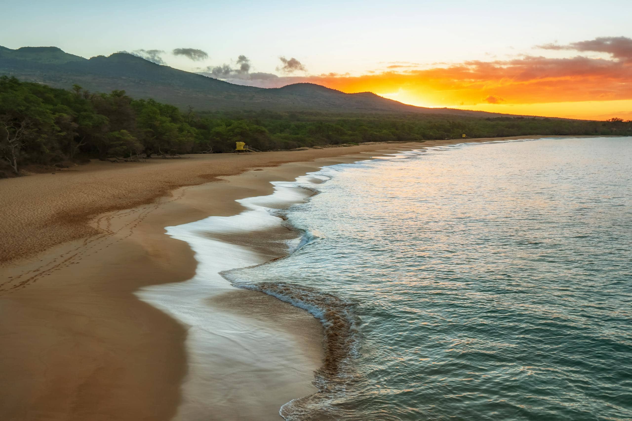 Serene sunset at Makena Beach, Maui, with ocean waves lapping the shore.