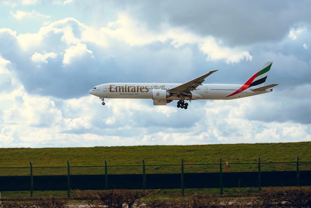 Emirates airplane flying in a clear sky, showcasing its iconic design and vibrant branding.