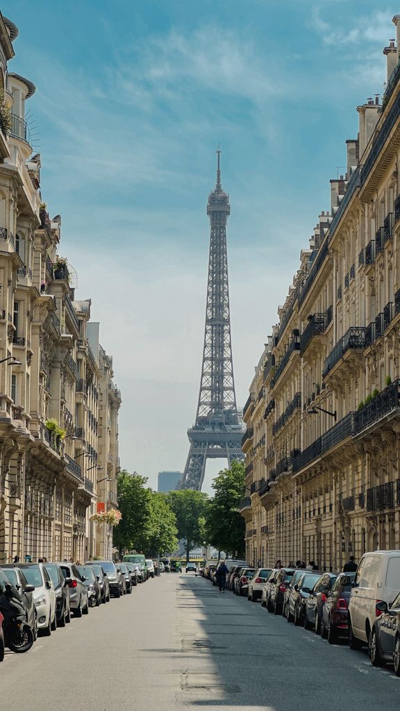 Charming street view of Paris with the iconic Eiffel Tower framed by classic buildings on a sunny day.