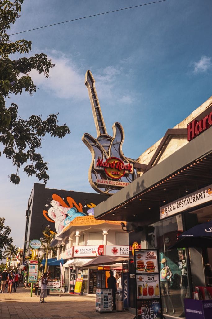 Vibrant street view of Hard Rock Café and surrounding shops in Playa del Carmen, Mexico.